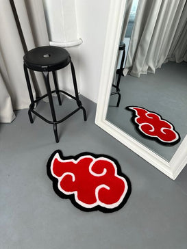 A stylish room featuring a red and black anime-inspired rug with a swirling cloud design. The rug is placed near a black stool and a large floor mirror, reflecting the rug’s design. 
